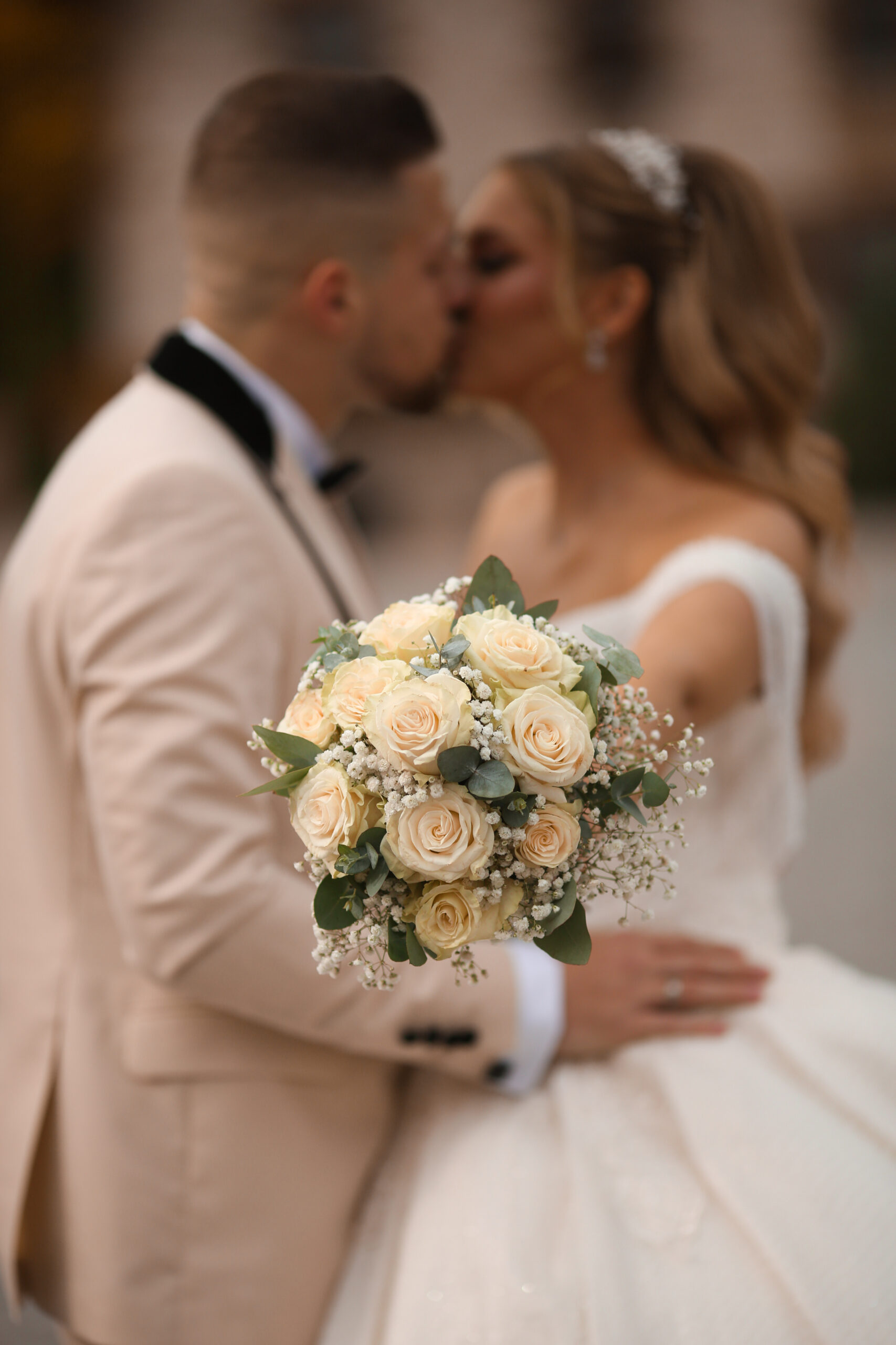 Romantischer Hochzeitsmoment in Hof – Brautstrauß & Kuss Brautpaar küsst sich romantisch, während die Braut den Brautstrauß hält – Hochzeit in Hof, Oberfranken